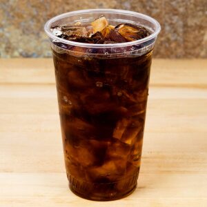 1114253 : Elementa Inc 24oz Compostable PLA Cold Cup filled with soda on a wooden table.