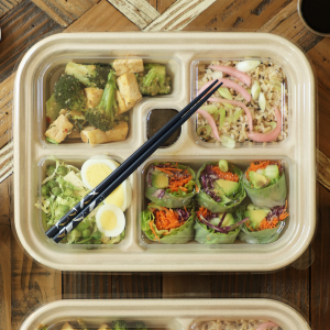 fiber five compartments compostable bento box containing sushi and vegetables.